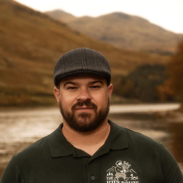 Guia da The Kilt Route com a camisa da empresa, diante de um lago